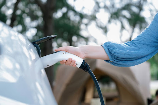 woman holding ev charging port going in car